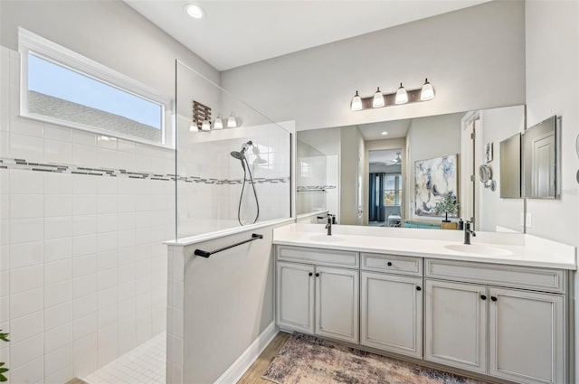 bathroom featuring tiled shower, vanity, and wood-type flooring