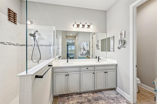 bathroom featuring vanity, hardwood / wood-style floors, toilet, and tiled shower