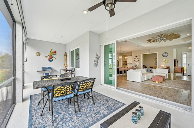 sunroom featuring a raised ceiling and ceiling fan