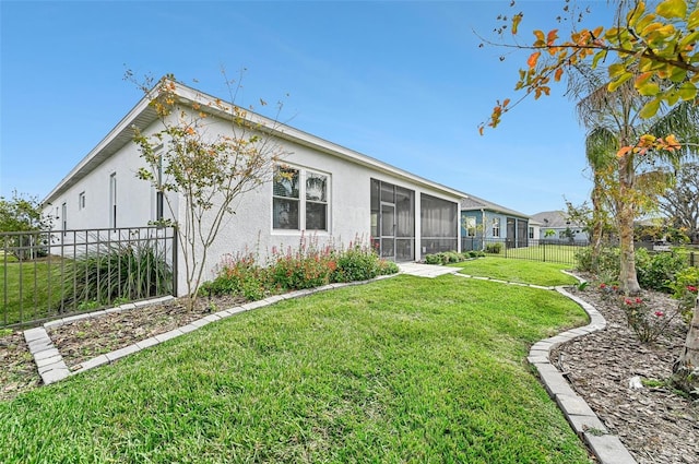 rear view of house featuring a sunroom and a lawn