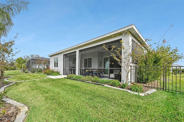 rear view of house with a sunroom, a yard, and ceiling fan