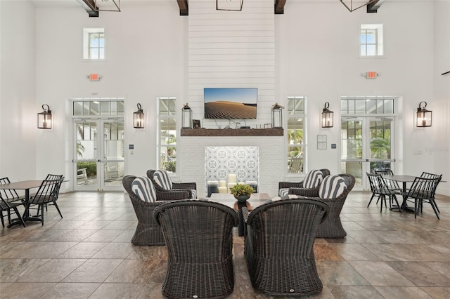 dining room featuring a towering ceiling, a fireplace, and beam ceiling