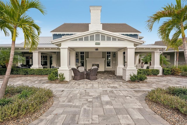 back of property featuring an outdoor fireplace and a patio