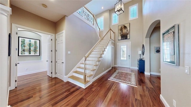 entryway with a towering ceiling and dark hardwood / wood-style floors