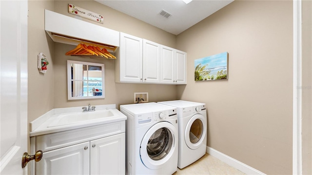 washroom featuring cabinets, light tile patterned floors, washing machine and dryer, and sink