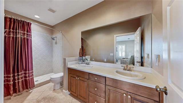 bathroom featuring a tile shower, tile patterned flooring, vanity, and toilet