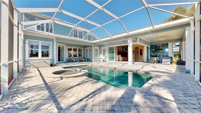 view of pool with glass enclosure, ceiling fan, a patio area, and an in ground hot tub