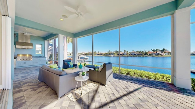 sunroom / solarium featuring a water view and ceiling fan