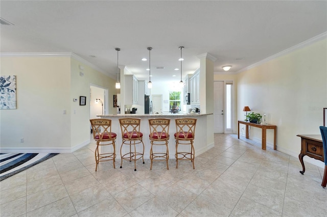 kitchen featuring pendant lighting, kitchen peninsula, white cabinetry, a kitchen breakfast bar, and ornamental molding