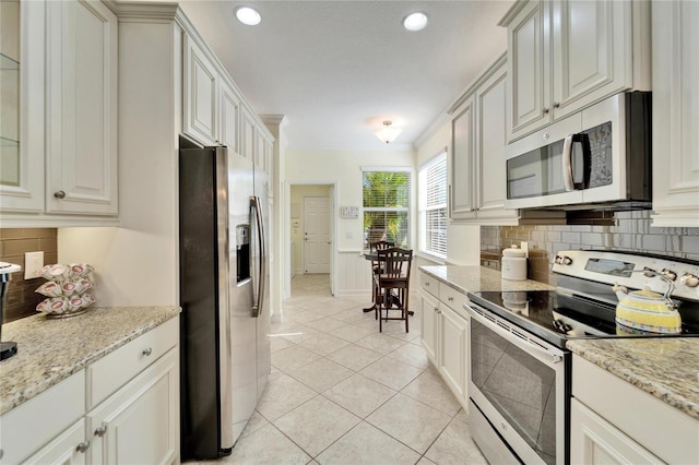 kitchen featuring light stone countertops, light tile patterned floors, white cabinetry, and appliances with stainless steel finishes