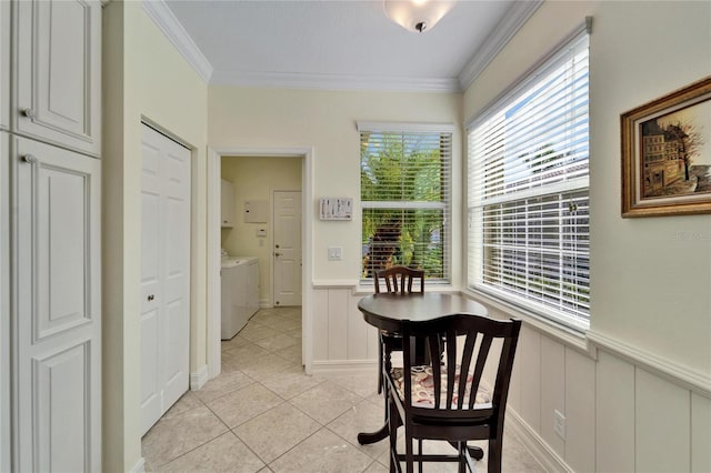 corridor with light tile patterned flooring, crown molding, and washer and clothes dryer