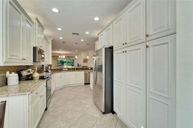 kitchen with white cabinetry, stainless steel appliances, sink, hanging light fixtures, and light stone counters