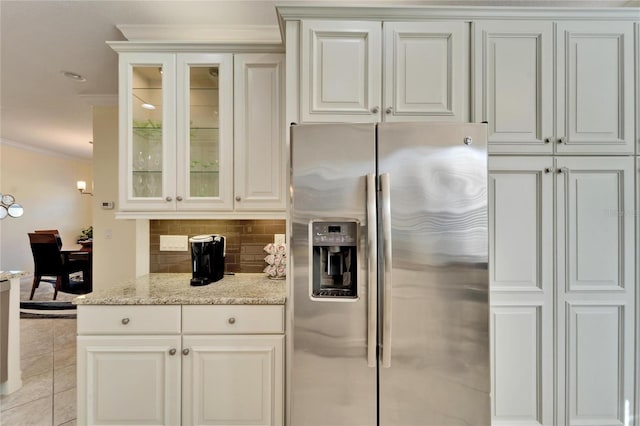 kitchen with white cabinetry, tasteful backsplash, stainless steel fridge, light stone counters, and crown molding