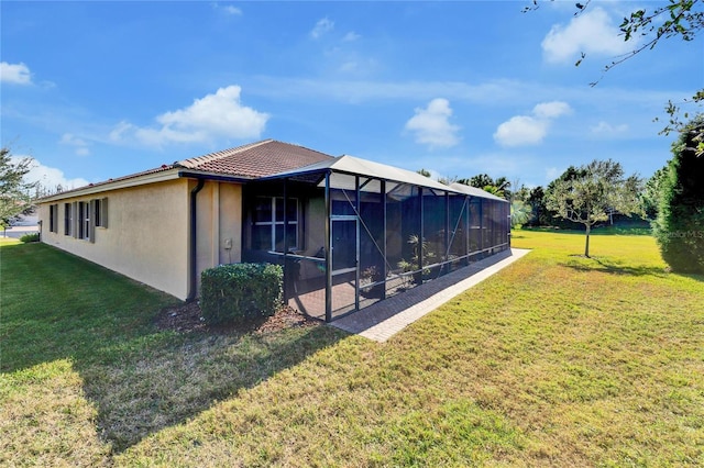 view of home's exterior with glass enclosure and a lawn