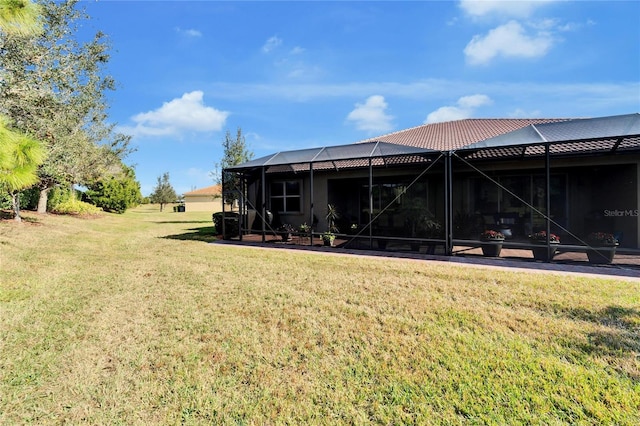 rear view of property with a lawn and glass enclosure