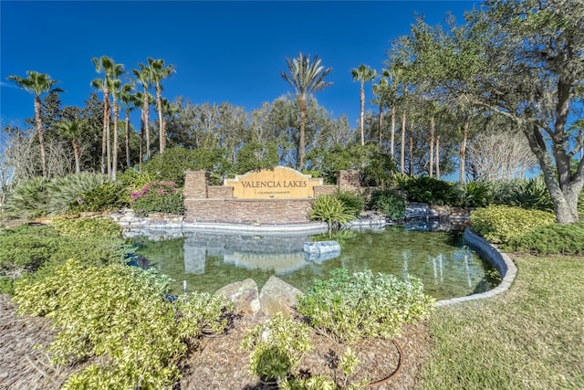 community / neighborhood sign featuring a small pond