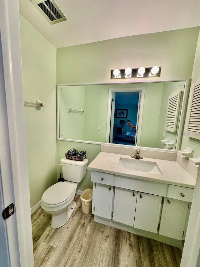 bathroom with hardwood / wood-style flooring, toilet, and vanity