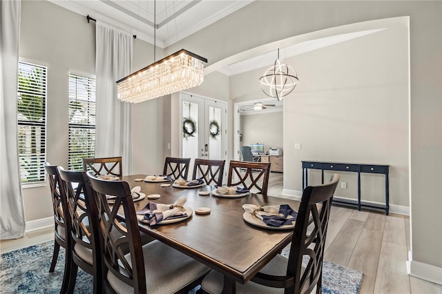 dining area with a healthy amount of sunlight, light hardwood / wood-style floors, crown molding, and ceiling fan with notable chandelier