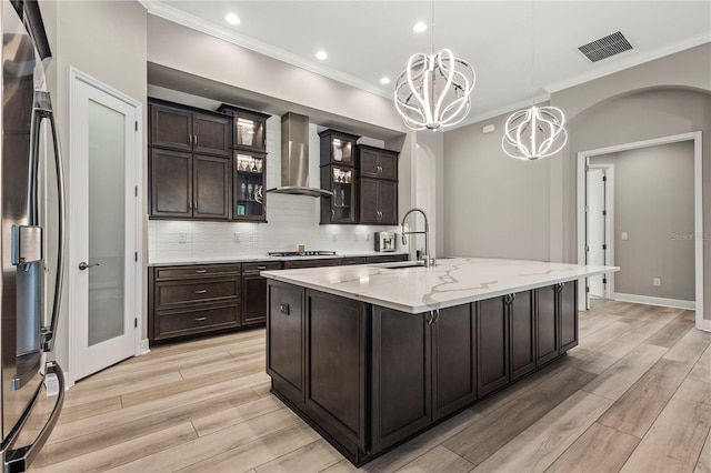 kitchen featuring sink, wall chimney exhaust hood, a spacious island, dark brown cabinetry, and a chandelier