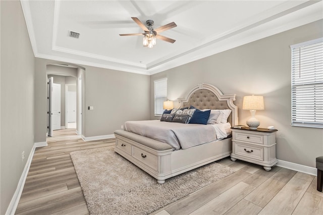 bedroom featuring crown molding, ceiling fan, light hardwood / wood-style floors, and a tray ceiling