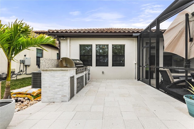 view of patio / terrace with an outdoor kitchen, a lanai, central air condition unit, and area for grilling