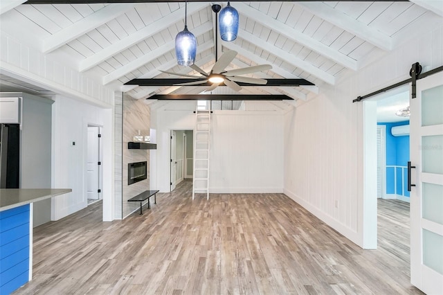 unfurnished living room featuring wood-type flooring, ceiling fan, a barn door, vaulted ceiling with beams, and wood walls