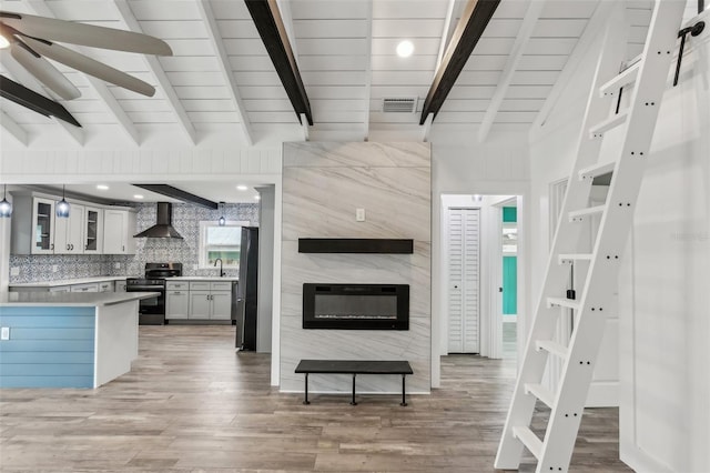 kitchen featuring wall chimney exhaust hood, light wood-type flooring, appliances with stainless steel finishes, and sink