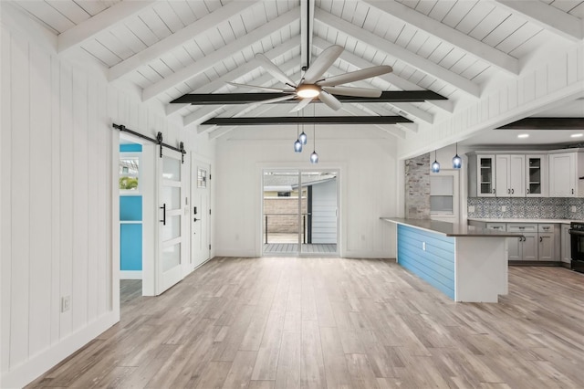 kitchen featuring light hardwood / wood-style floors, pendant lighting, a barn door, and tasteful backsplash