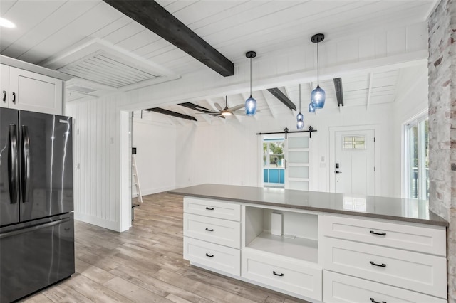 kitchen featuring fridge, white cabinetry, a barn door, pendant lighting, and ceiling fan