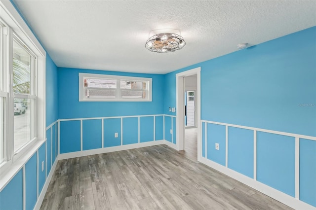 unfurnished room featuring hardwood / wood-style flooring, a healthy amount of sunlight, and a textured ceiling