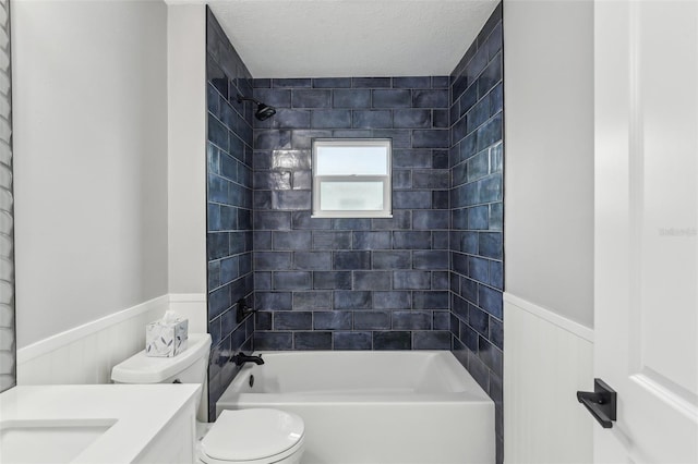 full bathroom with toilet, a textured ceiling, tiled shower / bath, and vanity