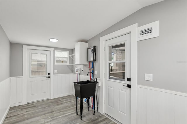 interior space featuring light wood-type flooring, vaulted ceiling, and sink