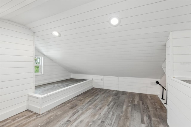 bathroom with wooden walls, hardwood / wood-style floors, and lofted ceiling