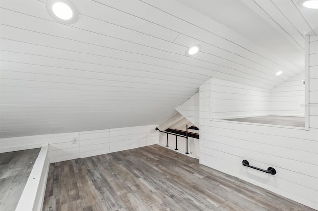 additional living space featuring hardwood / wood-style flooring, lofted ceiling, and wooden walls