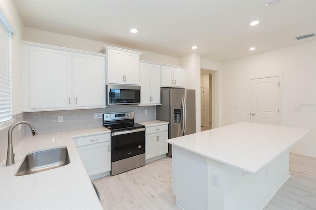 kitchen with a kitchen island, appliances with stainless steel finishes, sink, and white cabinets