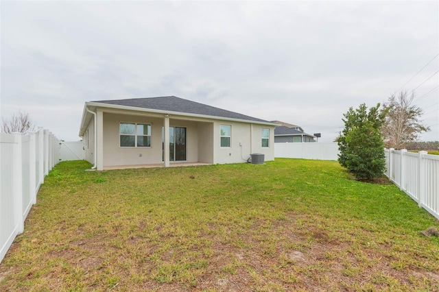 rear view of house featuring central AC unit and a lawn