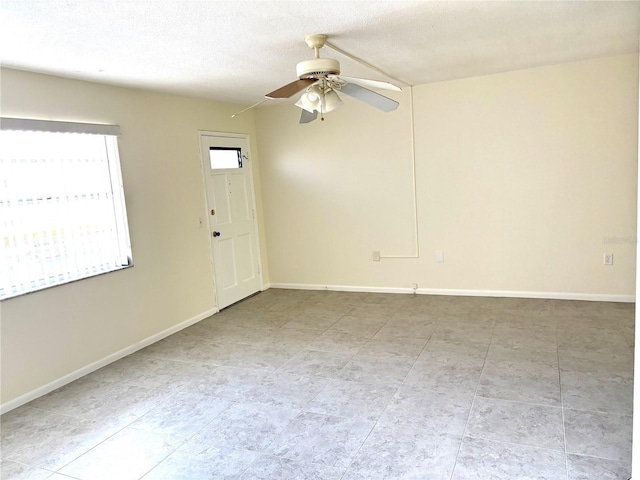 unfurnished room featuring baseboards, ceiling fan, and a textured ceiling