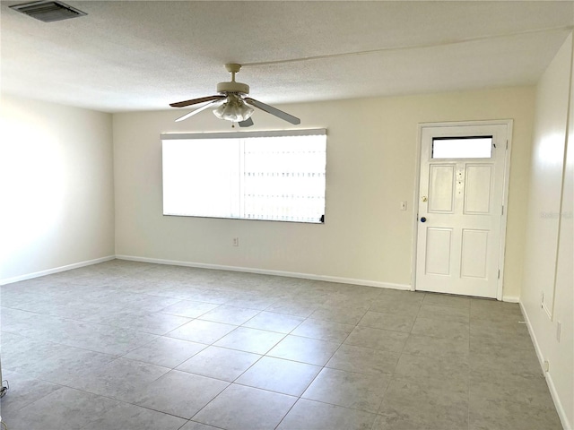 spare room with a ceiling fan, visible vents, tile patterned floors, and baseboards