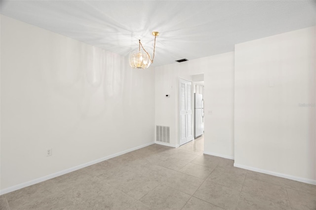 unfurnished room featuring a chandelier, visible vents, and baseboards