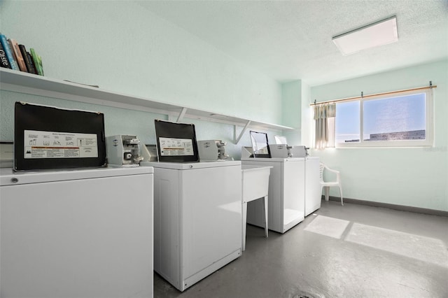 common laundry area featuring washing machine and dryer, a textured ceiling, and baseboards