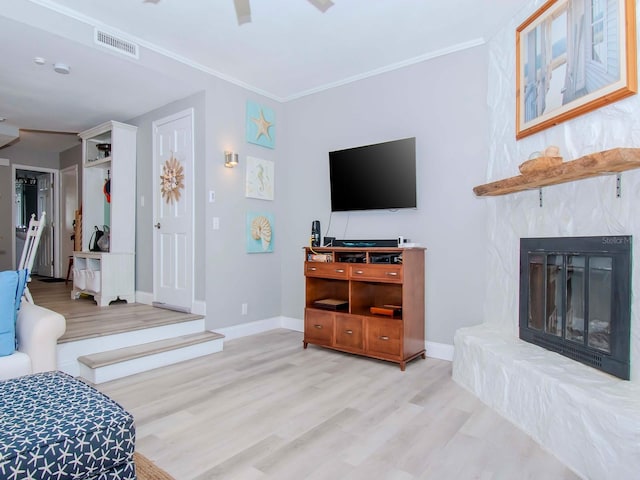 living room featuring light hardwood / wood-style floors, a large fireplace, and crown molding