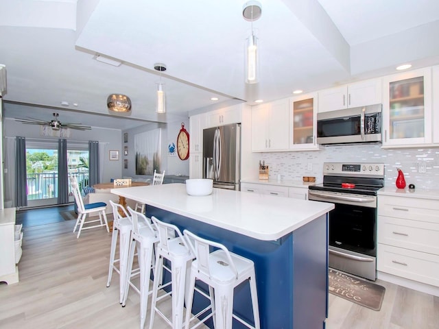 kitchen featuring a center island, decorative light fixtures, white cabinetry, stainless steel appliances, and tasteful backsplash