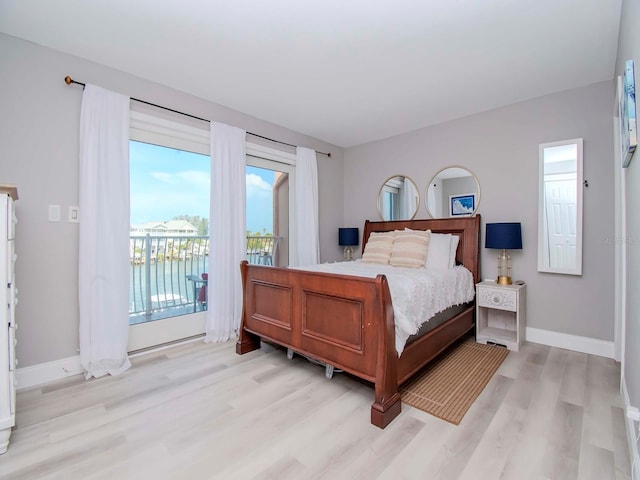 bedroom with access to outside, a water view, and light wood-type flooring