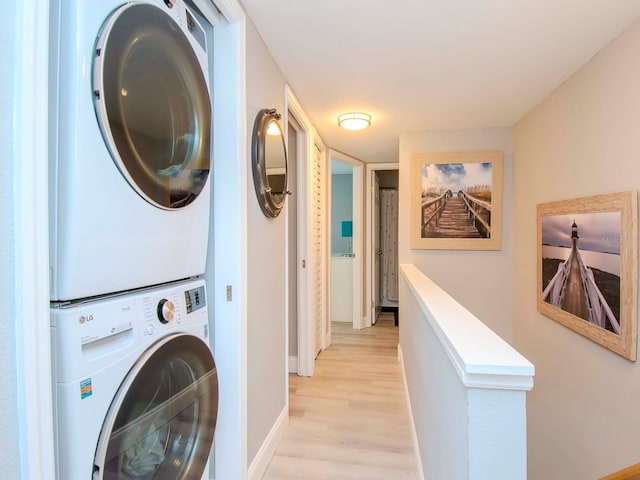 laundry room featuring stacked washer and dryer and light wood-type flooring