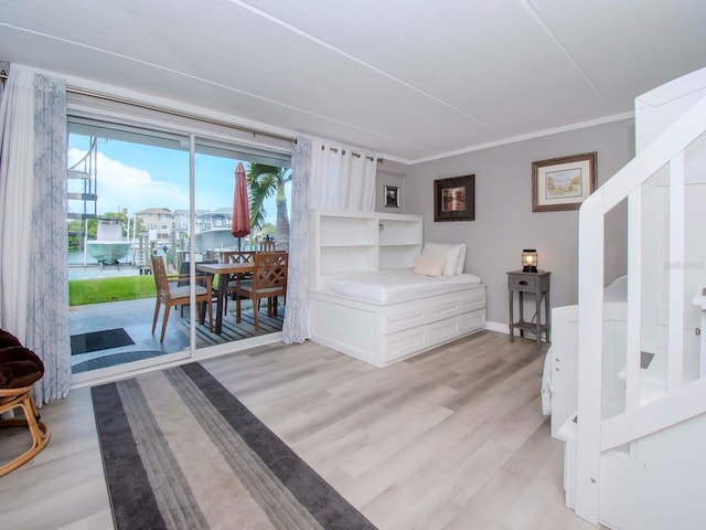 bedroom with access to outside, light wood-type flooring, and crown molding