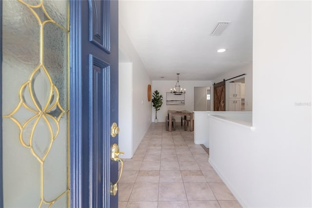 hallway with light tile patterned floors, a barn door, and a chandelier