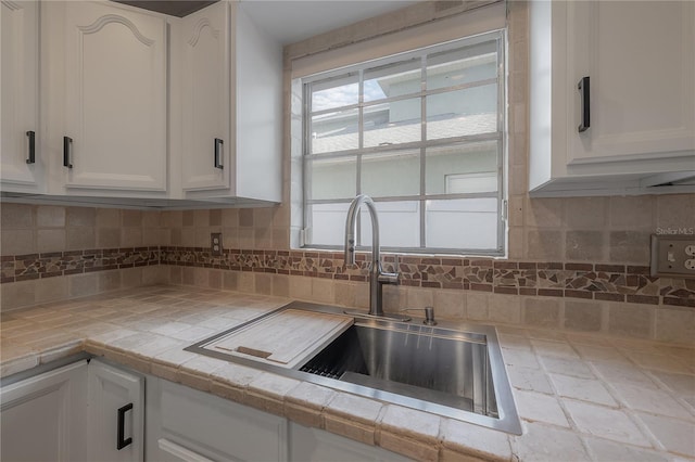 kitchen featuring white cabinetry, sink, tile countertops, and tasteful backsplash