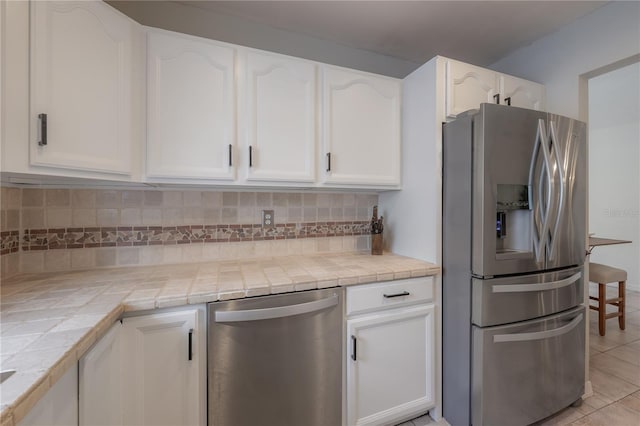 kitchen with white cabinetry, backsplash, tile countertops, and appliances with stainless steel finishes