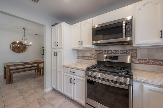 kitchen featuring stainless steel appliances, white cabinetry, light tile patterned flooring, and backsplash