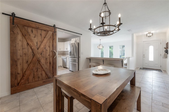 dining room with light tile patterned flooring, a barn door, and a chandelier